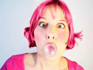 girl with pink hair blowing bubble